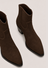 A pair of dark brown suede ankle boots with pointed toes and low block heels, shown from a high-angle perspective on a light gray background.