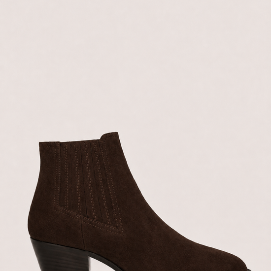 A dark brown suede ankle boot with a low block heel and pointed toe, shown from a side profile against a light beige background.