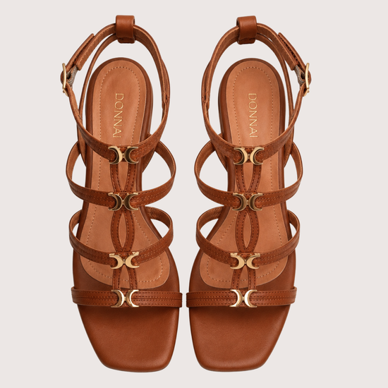 Pair of brown strappy sandals on a light beige background