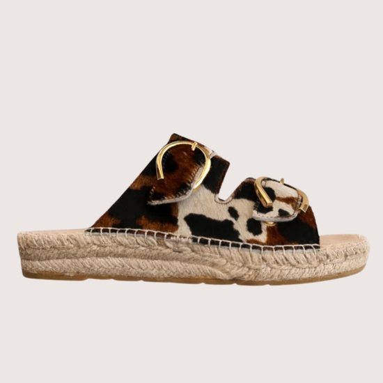 Cow print sandal with gold buckles and a woven sole 