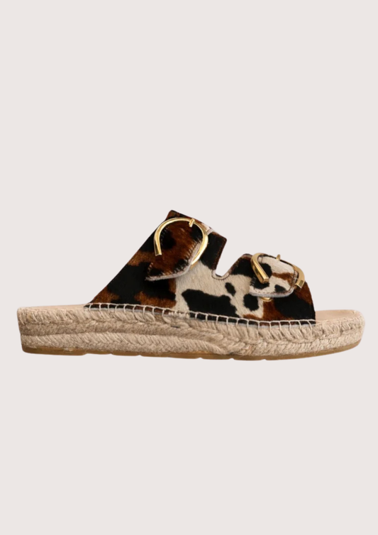 Cow print sandal with gold buckles and a woven sole 