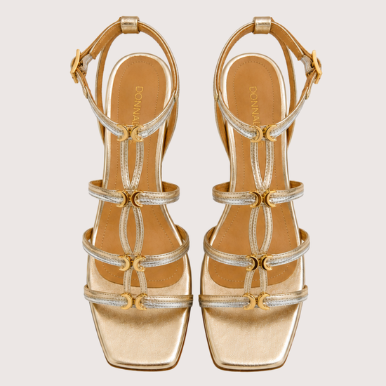 Gold and silver sandals with straps on a light gray background