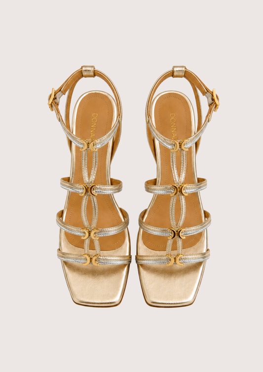 Gold and silver sandals with straps on a light gray background