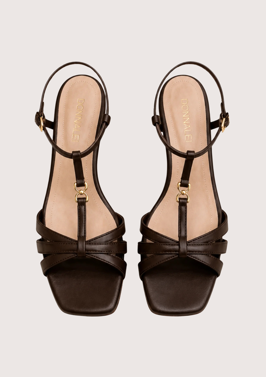 Pair of brown strappy sandals on a light beige background