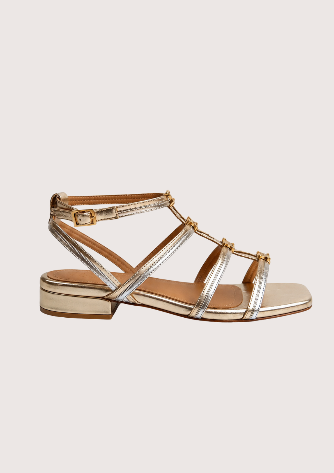 Gold sandal with a black heel on a light gray background