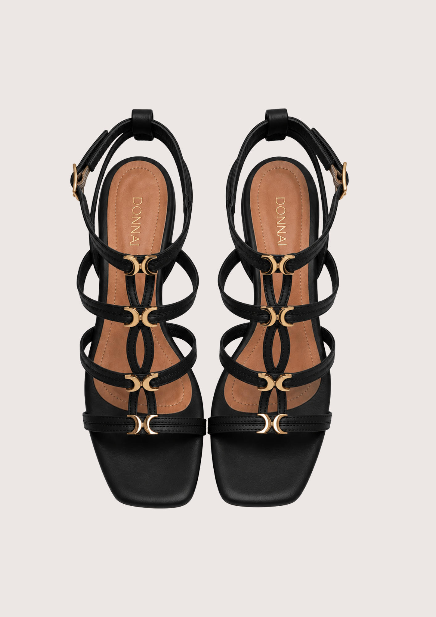 Black strappy sandals with gold accents on a light gray background