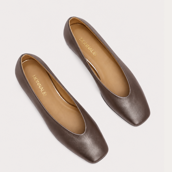 A pair of brown leather flats with square toes and low block heels, shown from a top-down view on a light gray background. The brand name 'M'ANNALE' is printed in gold on the tan insoles.