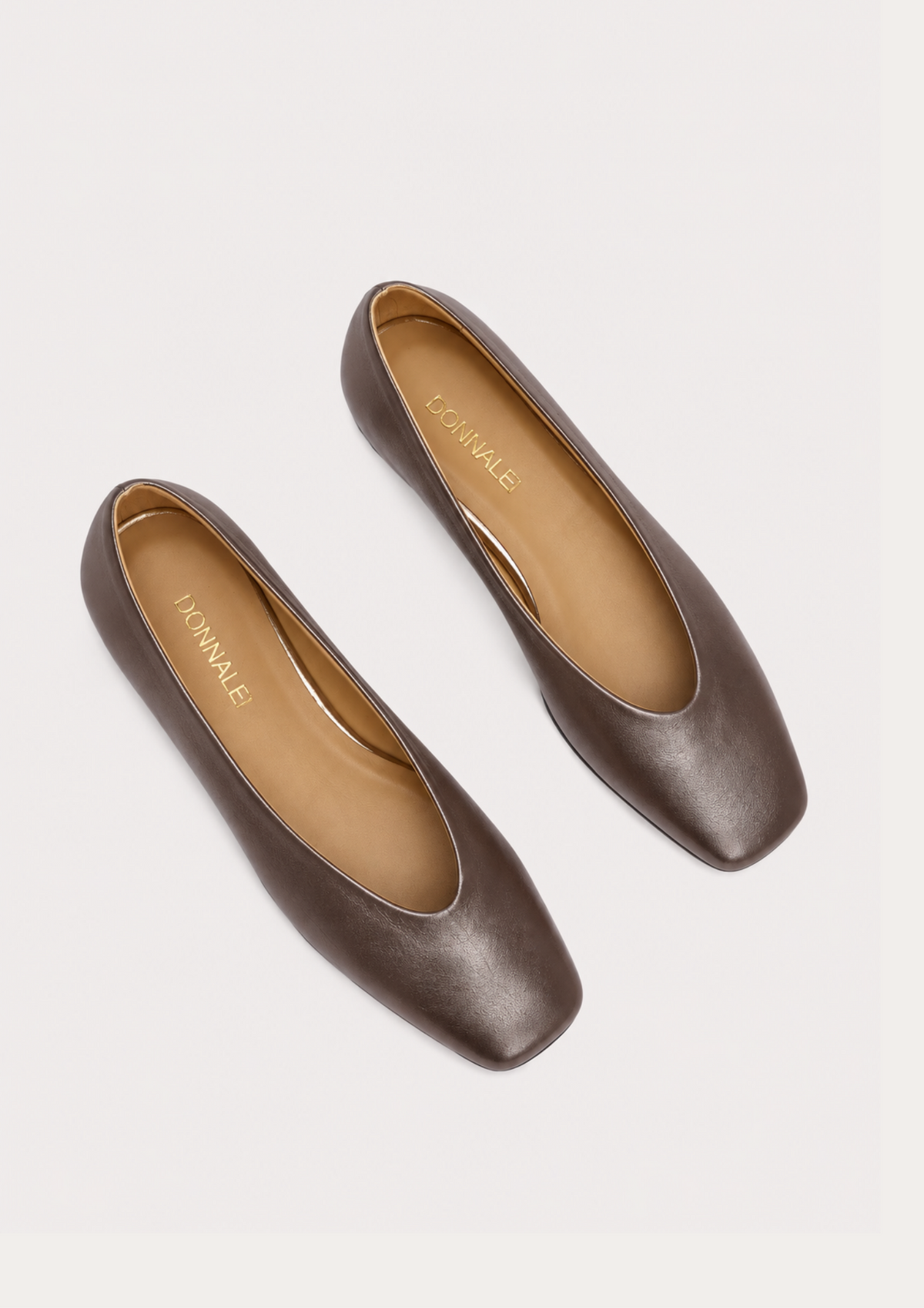 A pair of brown leather flats with square toes and low block heels, shown from a top-down view on a light gray background. The brand name 'M'ANNALE' is printed in gold on the tan insoles.