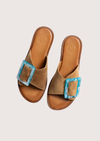 Brown sandals with a blue buckle on a light gray background