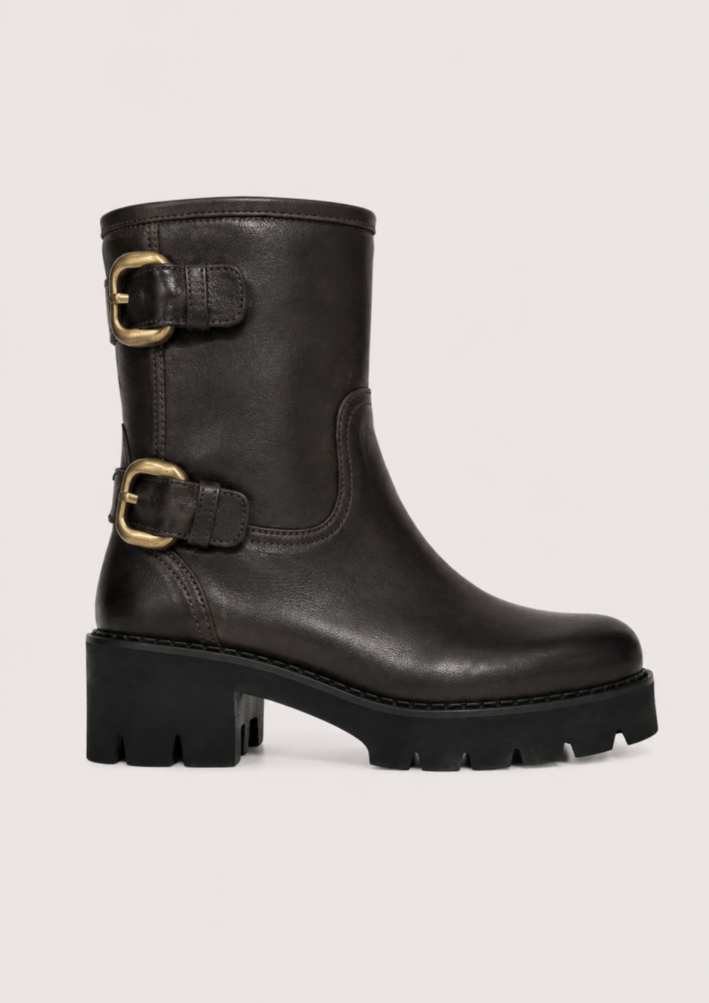 A black leather ankle boot with a chunky lug sole and two gold-tone buckle straps on the side, shown against a light gray background.
