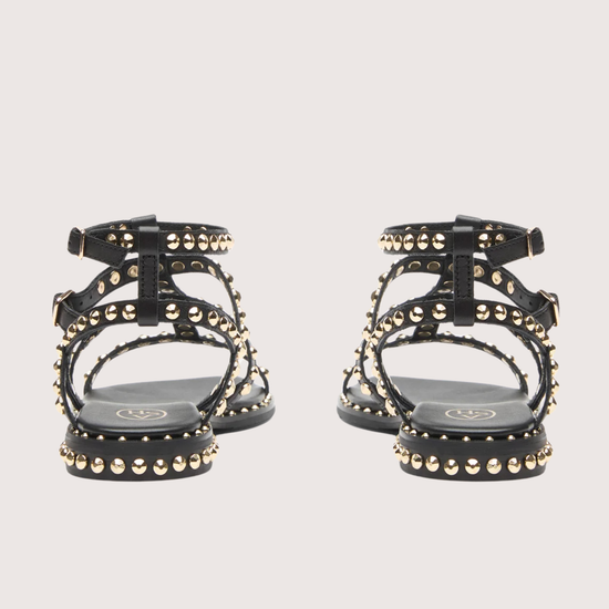 Black studded sandals on a light gray background