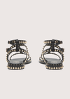 Black studded sandals on a light gray background