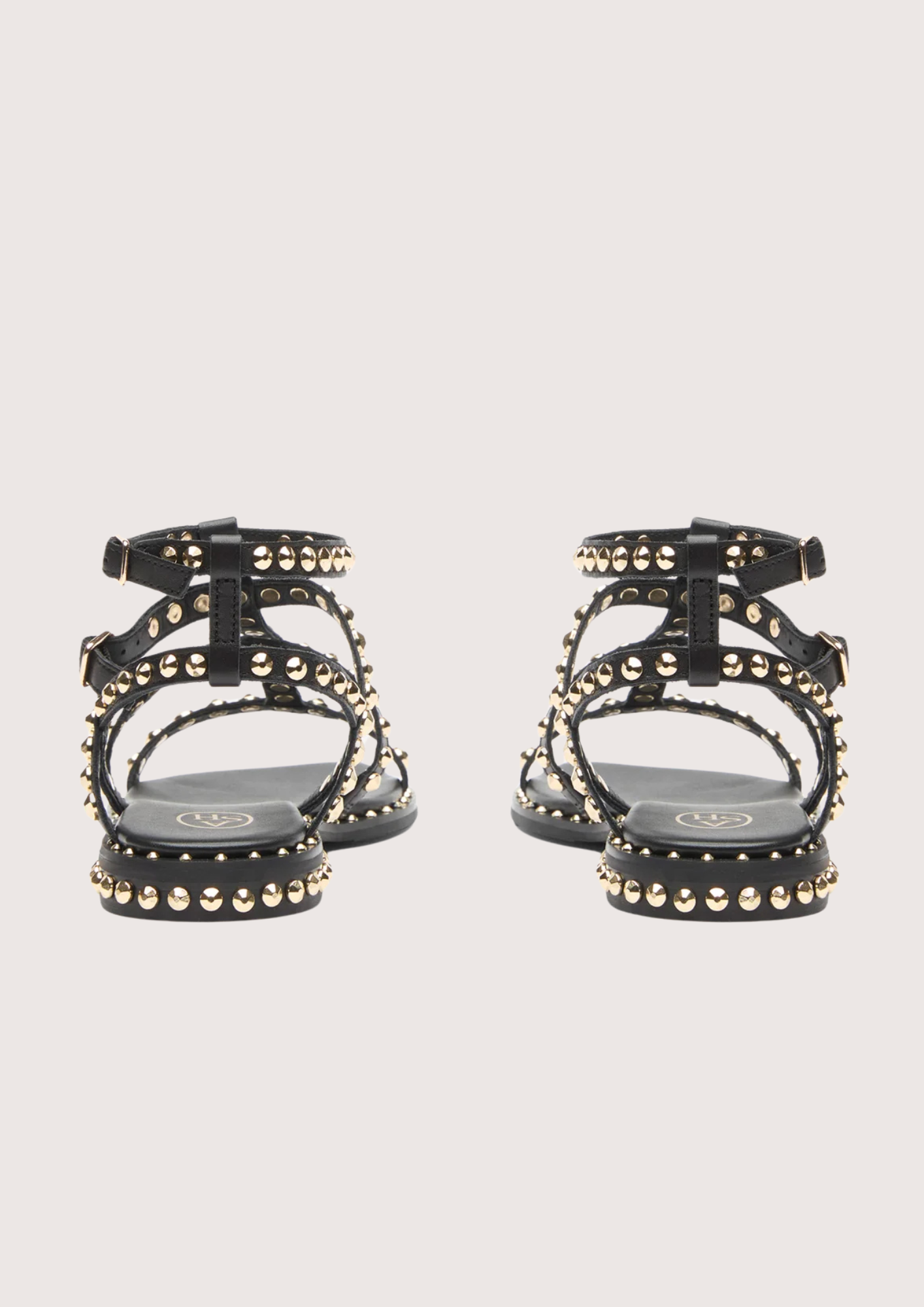 Black studded sandals on a light gray background