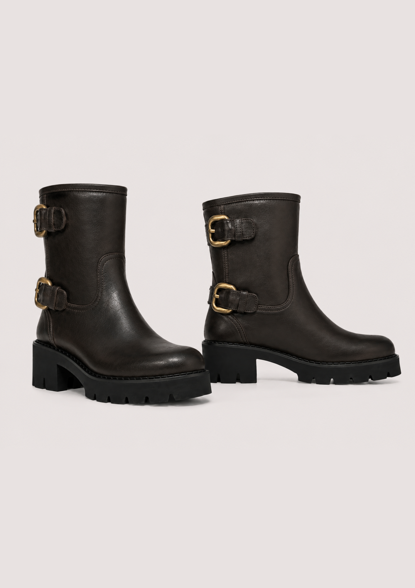A pair of dark brown leather ankle boots with chunky black block heels and gold-tone buckle straps, shown against a light gray studio background.