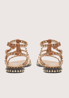 Pair of gold sandals with studded details on a white background rear view