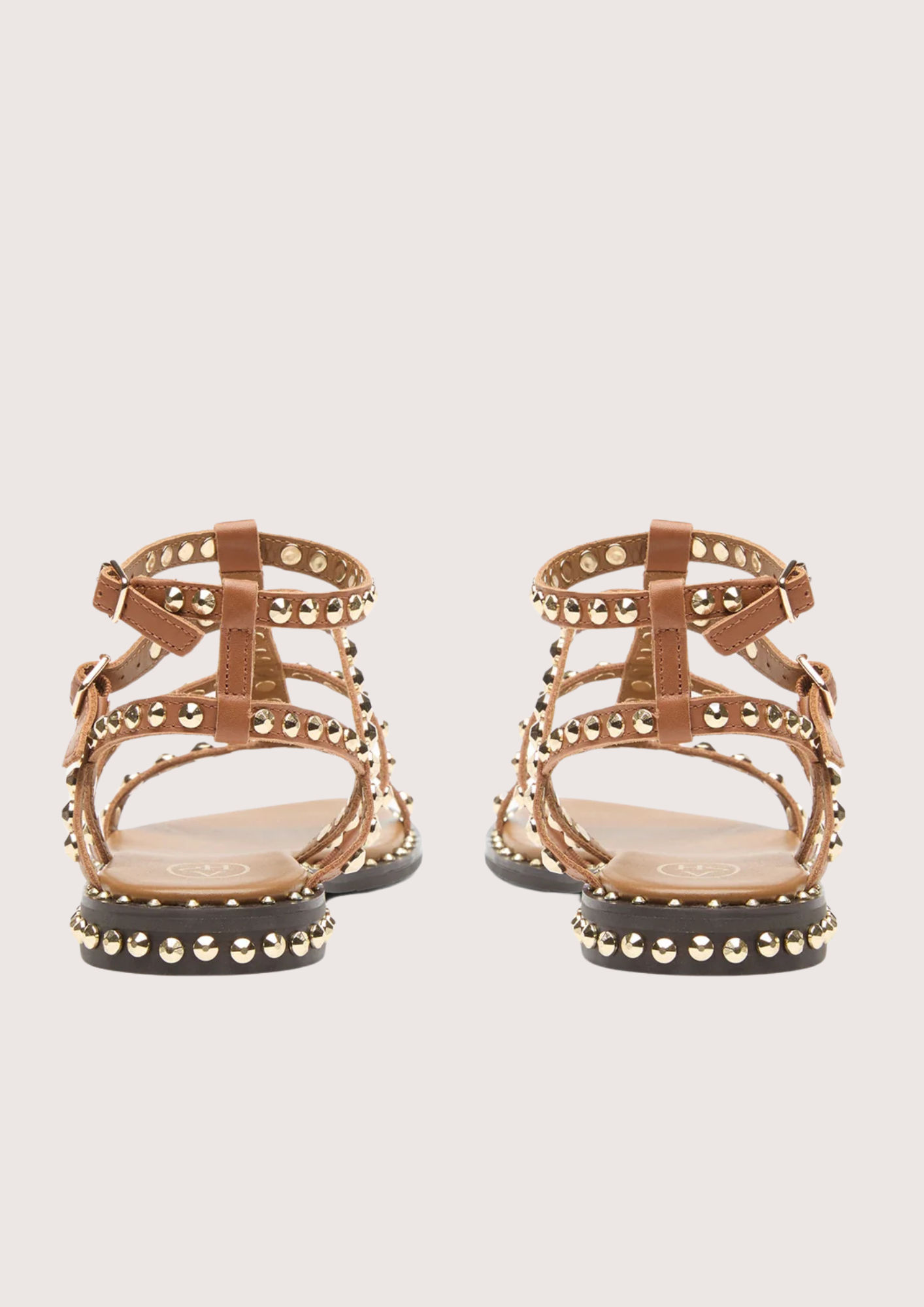 Pair of gold sandals with studded details on a white background rear view