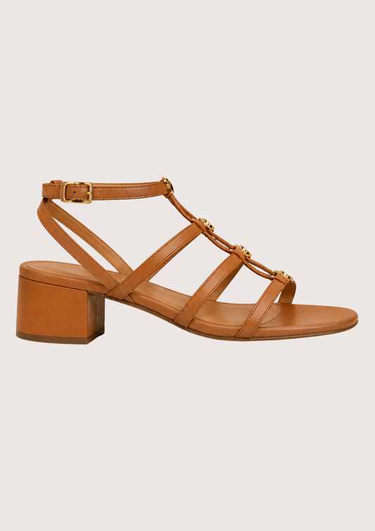 Tan sandal with a block heel on a light beige background