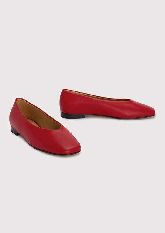 Pair of red leather flat shoes on a light gray background