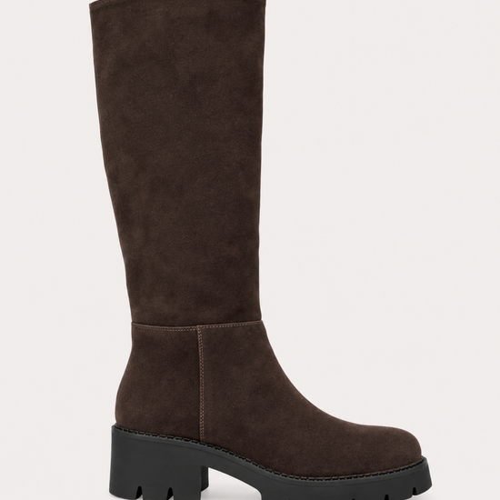 A dark brown suede knee-high boot with a chunky black lug sole and block heel, shown from a side profile on a light beige background.