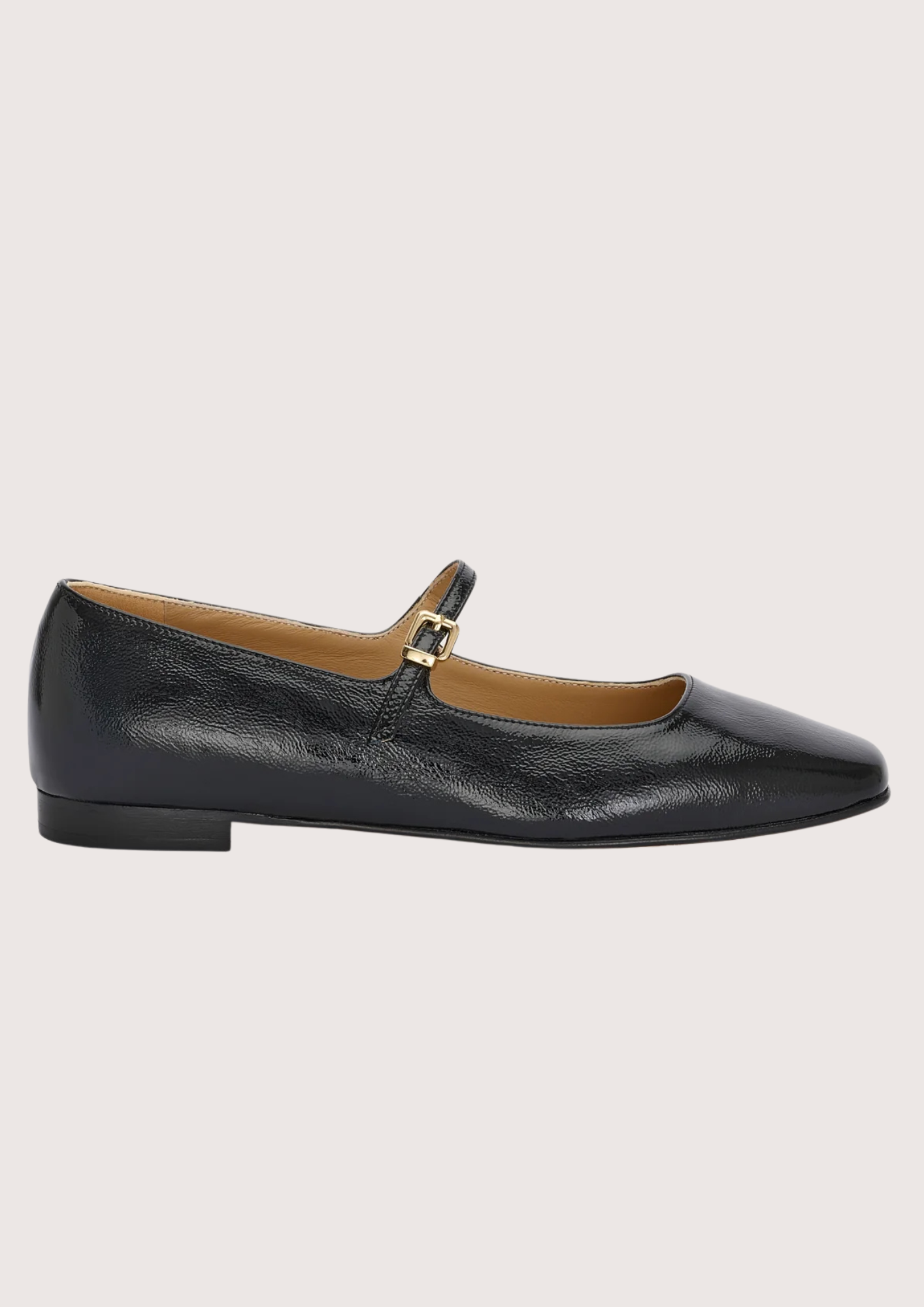 Black leather flat shoe with a gold buckle on a light gray background