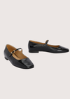Pair of black patent leather shoes with a square toe on a light gray background