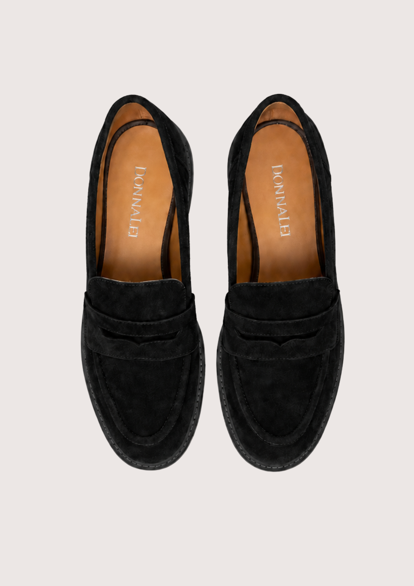 Black suede loafer on a plain grey background.