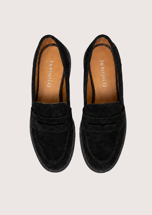 Black suede loafer on a plain grey background.