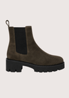 A Khaki suede Chelsea boot with a chunky black sole and a black elastic side panel, shown from a side profile on a light beige background.