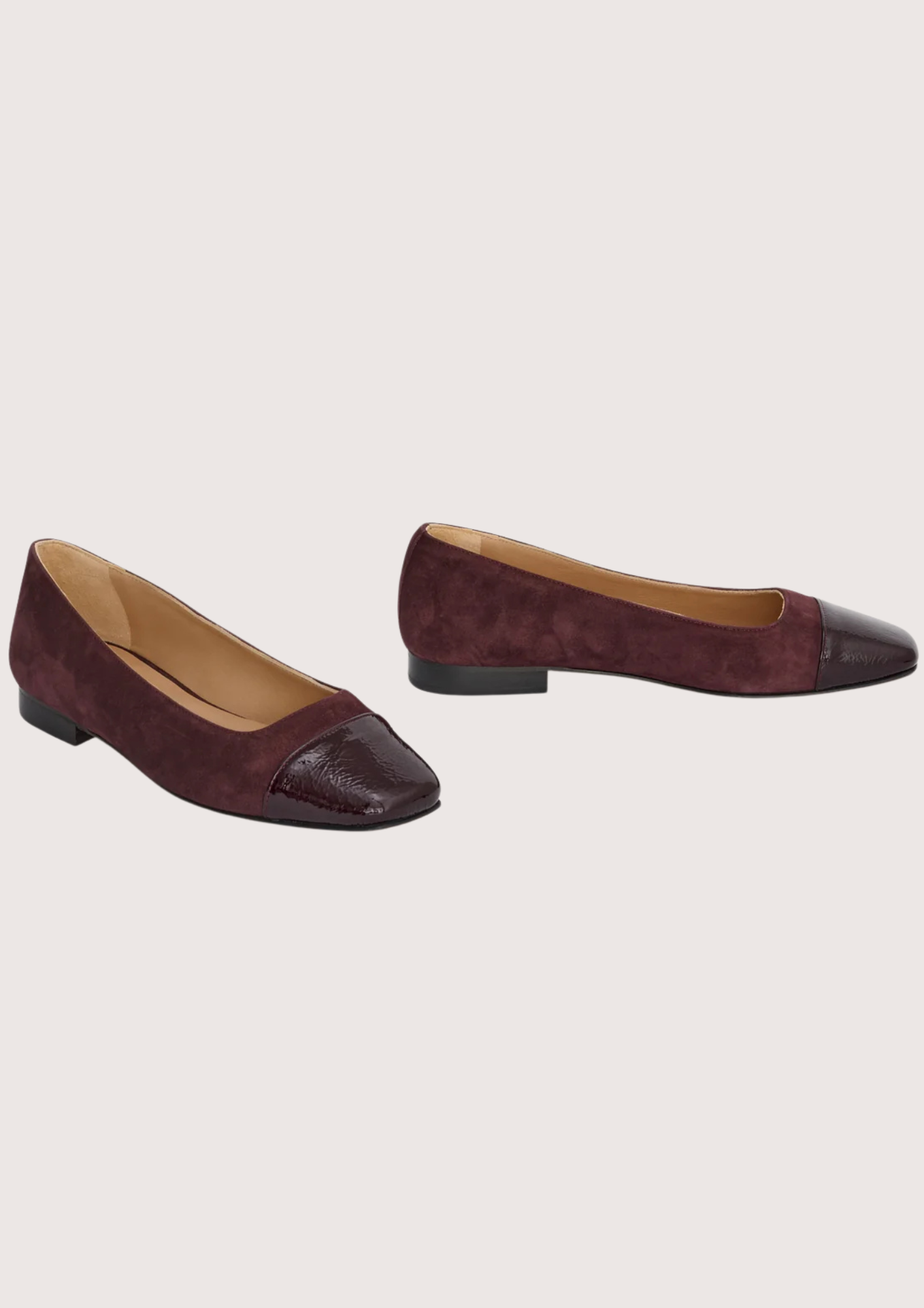 Pair of burgundy suede shoes on a light gray background