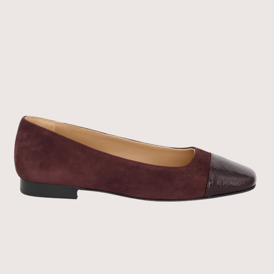 Burgundy flat shoe with cap toe on a light gray background