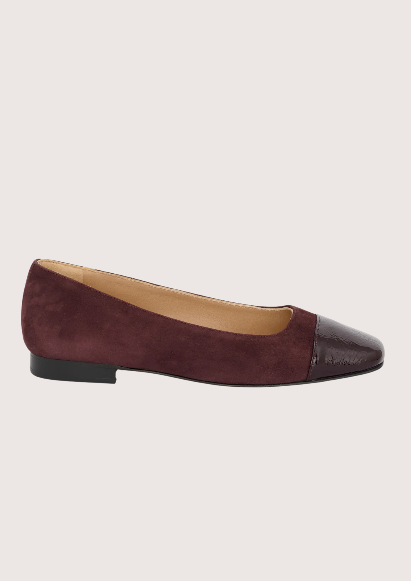 Burgundy flat shoe with cap toe on a light gray background