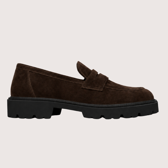 Brown suede loafer with a black sole on a light grey background