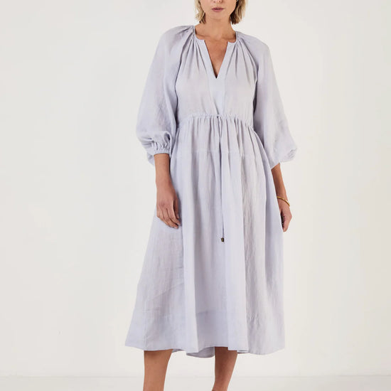 Woman wearing a light blue dress by Mondo Corsini on a white background