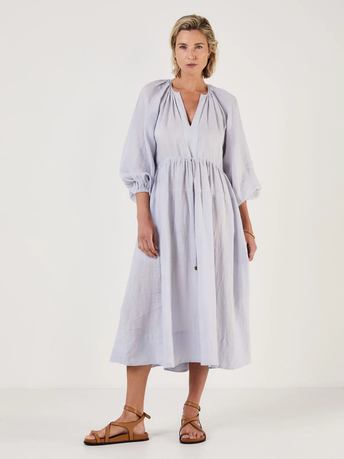 Woman wearing a light blue dress by Mondo Corsini on a white background
