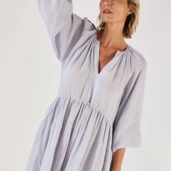Woman wearing a light blue dress by Mondo Corsini on a white background. Close up