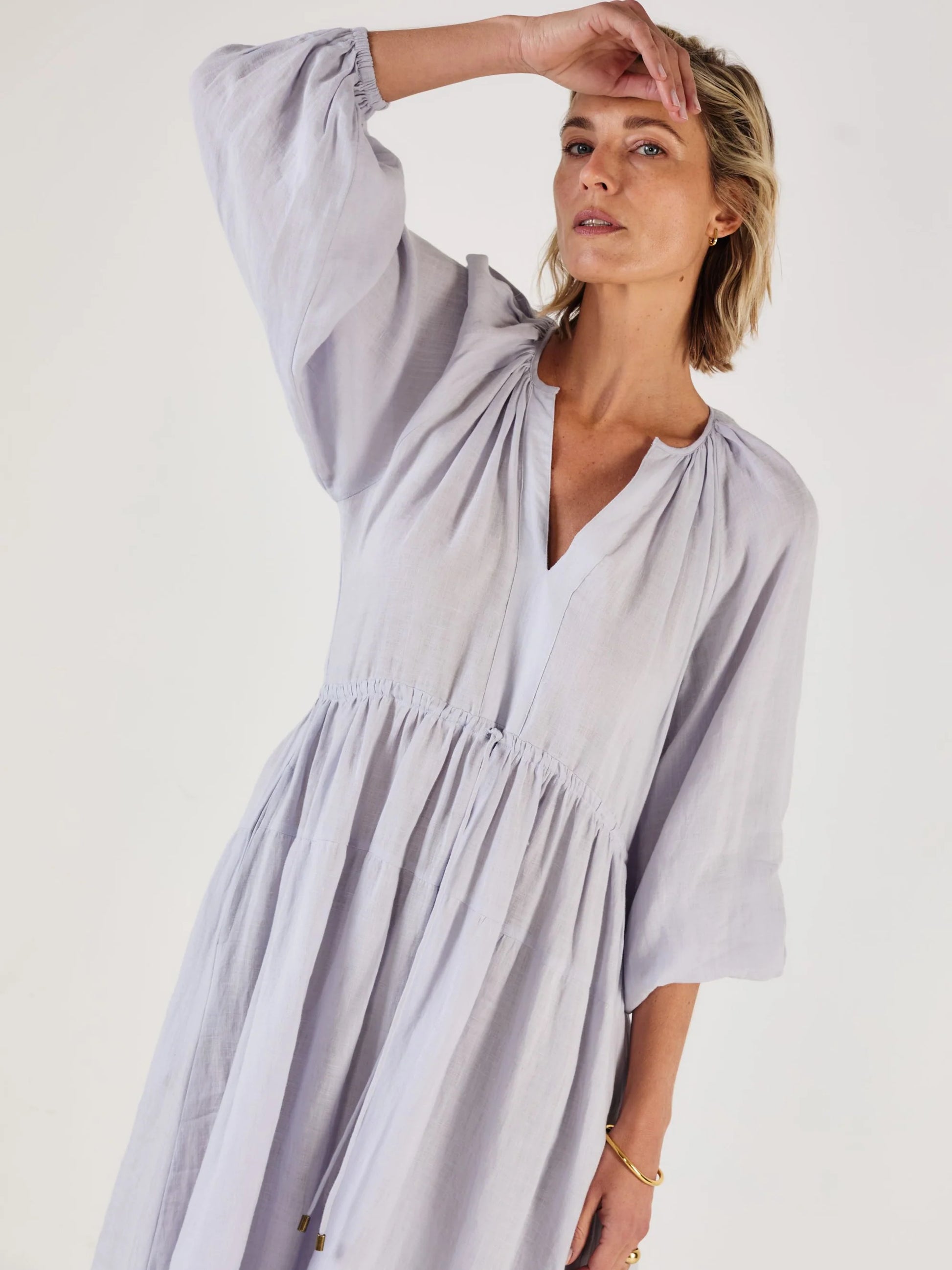 Woman wearing a light blue dress by Mondo Corsini on a white background. Close up