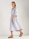 Woman wearing a light blue dress by Mondo Corsini on a white background. Side view