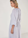 Woman wearing a light blue dress by Mondo Corsini on a white background. Side view close up