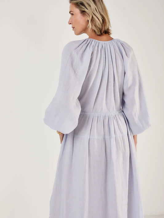 Woman wearing a light blue dress by Mondo Corsini on a white background. Rear view