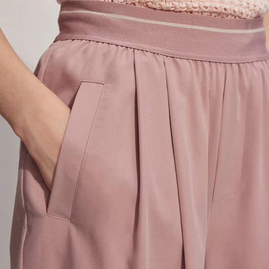 Pink pull on trousers with an elasticated waistband and side pockets close up of waistband