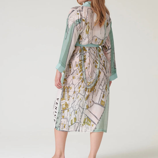 Woman wearing a patterned dress with a map design on a plain background