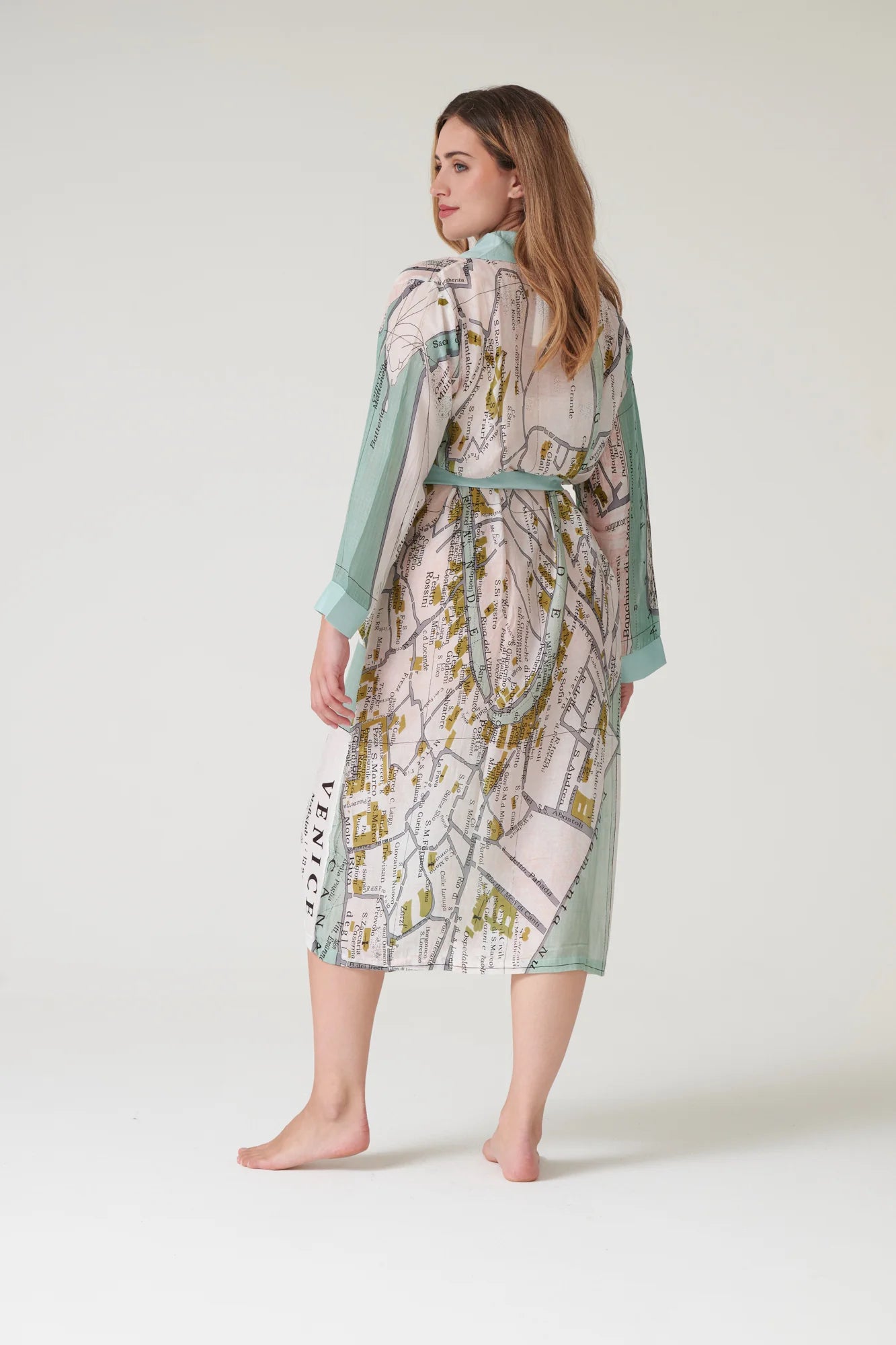 Woman wearing a patterned dress with a map design on a plain background