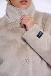 Close-up of a beige fleece jacket with buttons and a brand label.