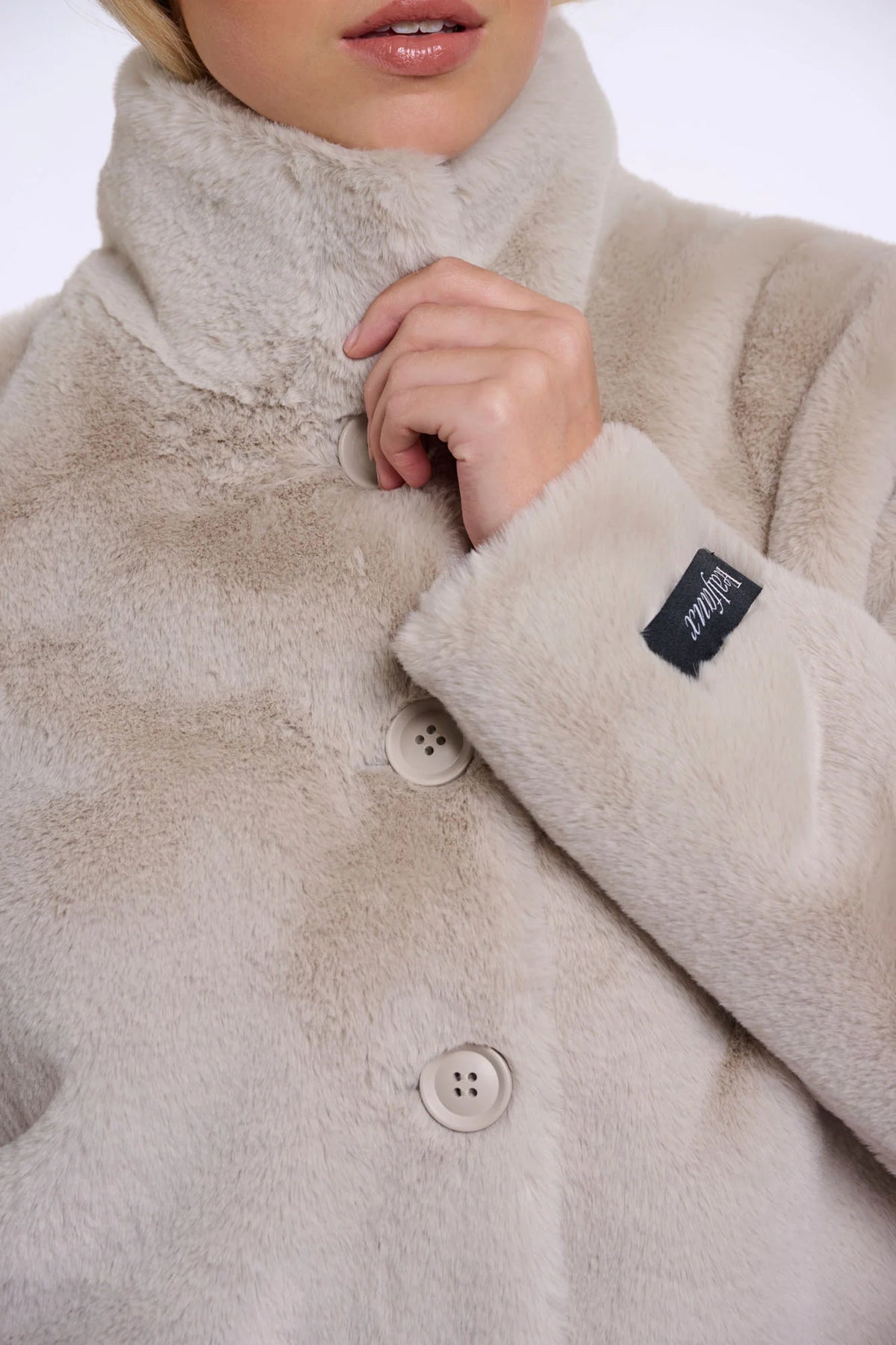 Close-up of a beige fleece jacket with buttons and a brand label.