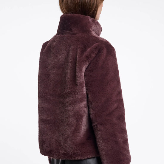 Person wearing a burgundy faux fur jacket on a white background