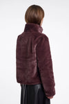 Person wearing a burgundy faux fur jacket on a white background