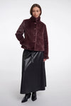 Woman wearing a brown textured jacket and black leather skirt on a white background
