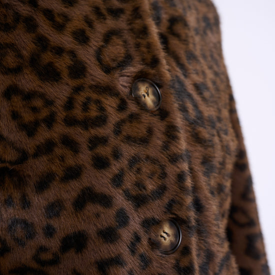 Close-up of a brown faux fur jacket with a black leopard print pattern and dark brown buttons.