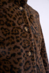 Close-up of a brown faux fur jacket with a black leopard print pattern and dark brown buttons.