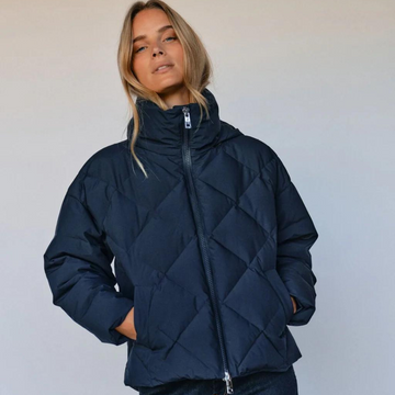 Girl wearing a navy quilted puffer style coat.